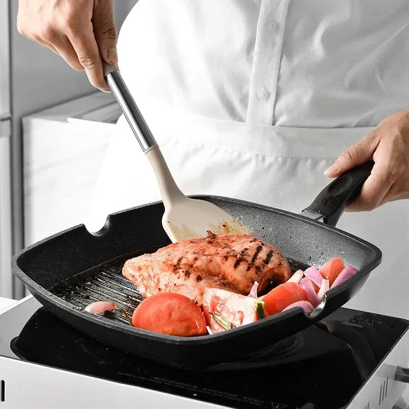 silicone turner lifting salmon in a nonstick grill pan
