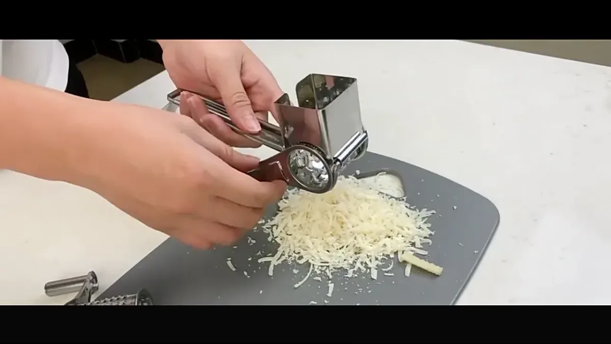 rotary cheese grater grating hard cheese onto a board