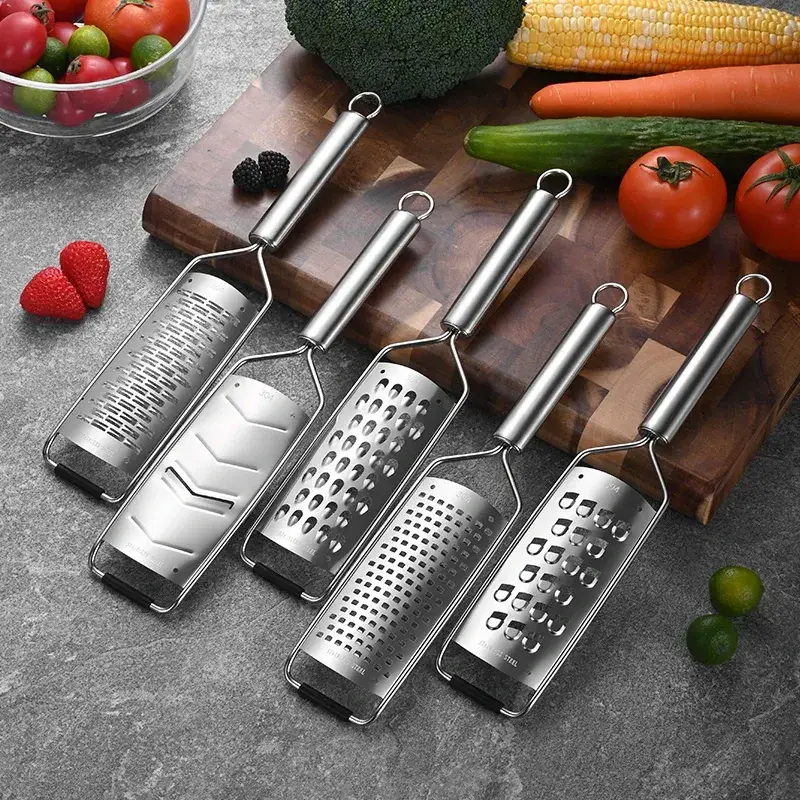five stainless steel handheld graters on a board with vegetables