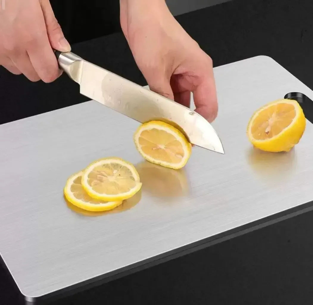 slicing lemon on a brushed stainless steel cutting board
